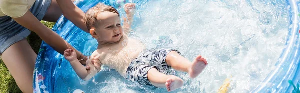 Madre bañarse sin camisa niño hijo en piscina inflable, bandera - foto de stock