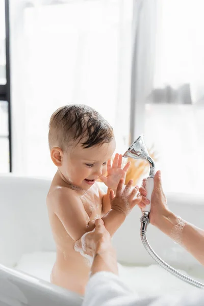 Mutter hält Duschkopf und badet glücklich Kleinkind Sohn — Stockfoto