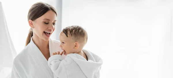 Amazed mother looking at toddler son in bathrobe, banner — Stock Photo