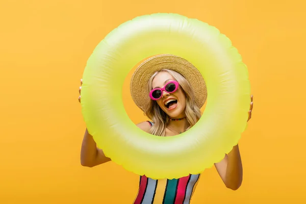 Excited woman in straw hat and swimsuit standing with inflatable ring isolated on yellow — Stock Photo