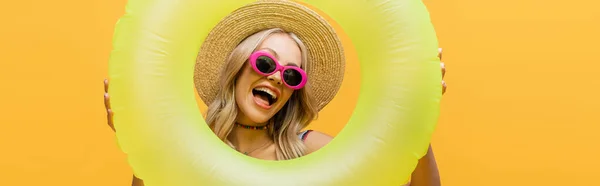 Femme excitée en chapeau de paille et maillot de bain debout avec anneau gonflable isolé sur jaune, bannière — Photo de stock