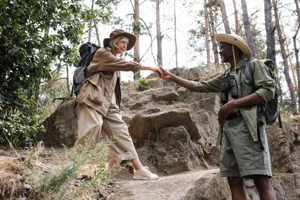 Escursionista afroamericano che tiene per mano la moglie anziana nella foresta — Foto stock