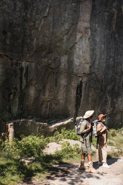 Touristes interraciaux avec des sacs à dos debout près de la falaise — Photo de stock