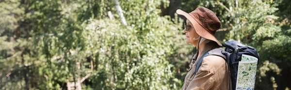 Side view of elderly tourist with backpack and map in forest, banner — Stock Photo