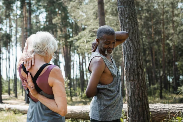 Hombre afroamericano haciendo ejercicio con su esposa mayor en el bosque - foto de stock