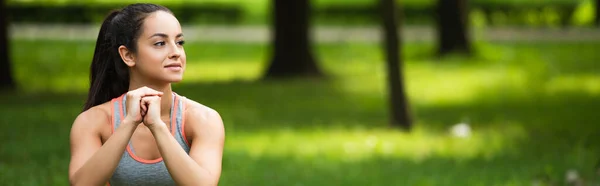 Pretty sportswoman with clenched hands exercising in park, banner — Stock Photo