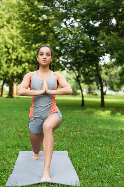 Joven mujer haciendo baja embestida pose en yoga mat en parque - foto de stock