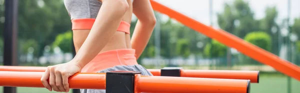 Cropped view of young woman exercising on parallel bars outside, banner — Stock Photo