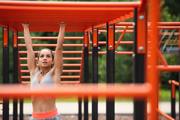 Athletic woman exercising on blurred horizontal ladder outside — Stock Photo