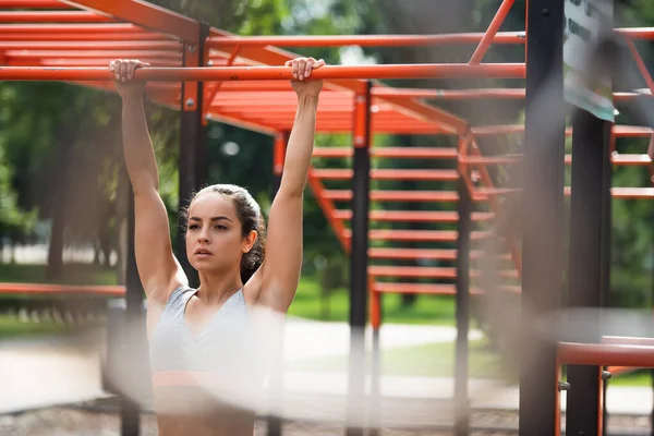 Jeune femme athlétique travaillant sur pull up bar dans la salle de gym extérieure — Photo de stock