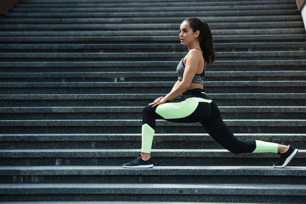 Comprimento total de mulher esportiva fazendo lunge em escadas fora — Fotografia de Stock