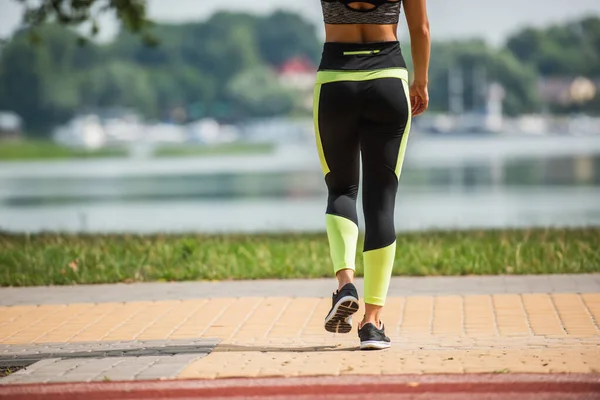 Cropped view of sportswoman walking near blurred lake — Stock Photo
