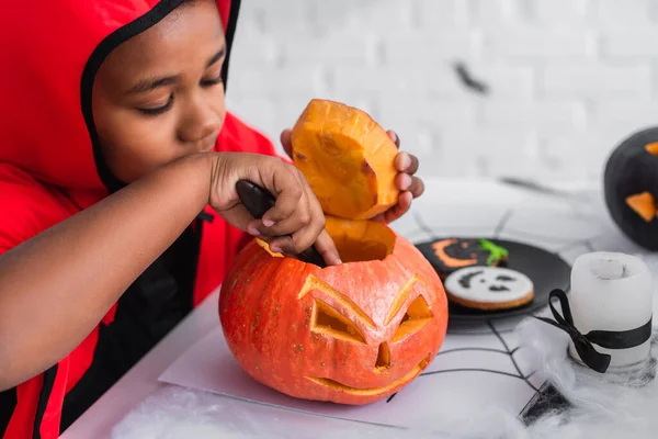 Afrikanisch-amerikanischer Junge im Halloween-Kostüm schnitzte Kürbis — Stockfoto