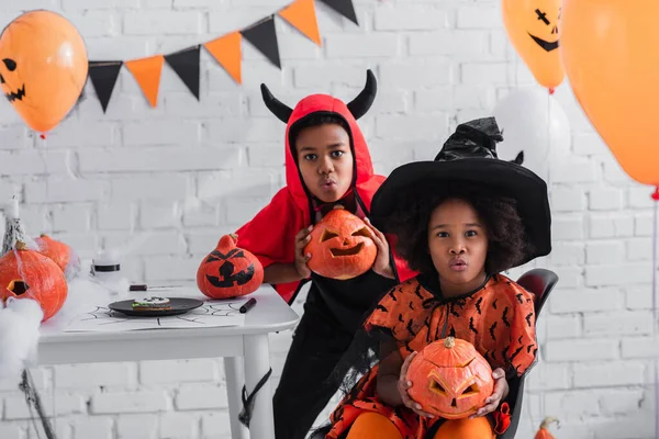 Assustador crianças afro-americanas em trajes de Halloween segurando abóboras esculpidas em casa — Fotografia de Stock