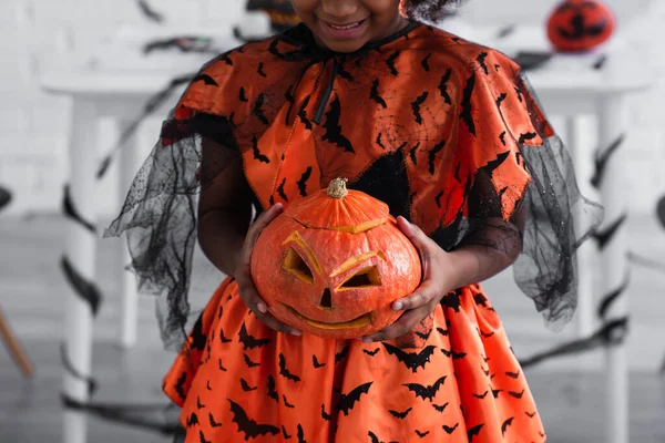 Cropped view of smiling african american kid holding carved pumpkin — Stock Photo