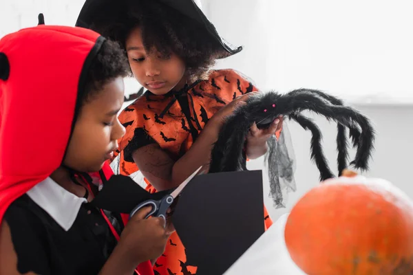 Africano americano bambino taglio nero carta sorella in costume tenuta giocattolo ragno — Foto stock