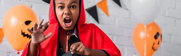 Дивний афроамериканський хлопчик в костюмі диявола Хелловін кричить, банер — стокове фото