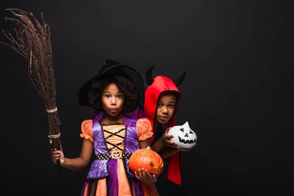 Crianças africanas americanas em trajes de Halloween segurando abóboras isoladas em preto — Fotografia de Stock
