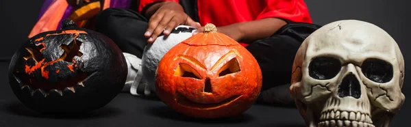 Cropped view of african american siblings in halloween costumes holding carved pumpkins on black, banner — Stock Photo