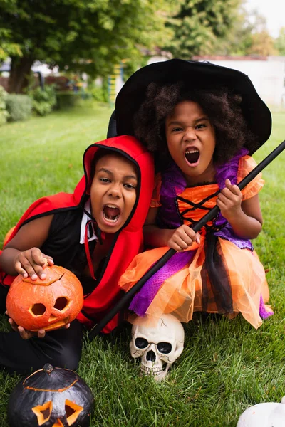 Gruselige afrikanisch-amerikanische Kinder in Halloween-Kostümen schreien beim Spielen auf dem Hinterhof — Stockfoto