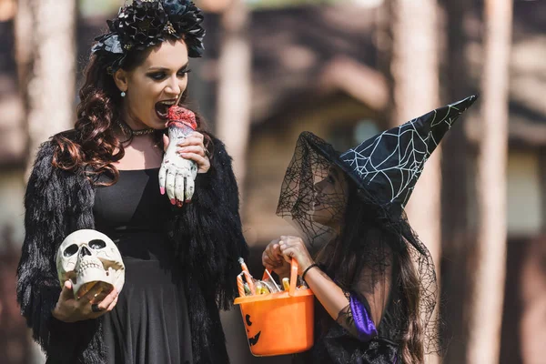 Woman in vampire halloween costume scaring daughter with toy hand — Stock Photo