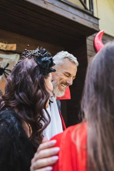 Excited man laughing with closed eyes near blurred wife and daughter on halloween — Stock Photo