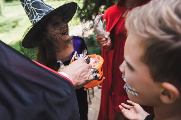 Homem desfocado dando doces para crianças em trajes de Halloween — Fotografia de Stock