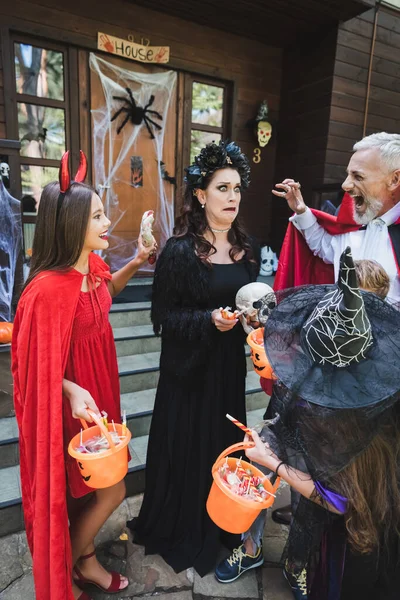 Famiglia spettrale in costumi di Halloween spaventosa madre spaventata vicino cottage — Foto stock