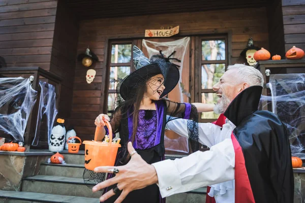 Pai animado e filha em trajes de Halloween perto de casa com decoração — Fotografia de Stock