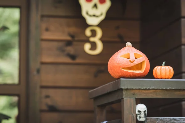 Carved pumpkin and spooky skull on porch fence of wooden cottage — Stock Photo
