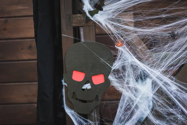 Filet d'araignée avec des araignées de jouet près du crâne effrayant de coupe de papier sur la clôture en bois — Photo de stock