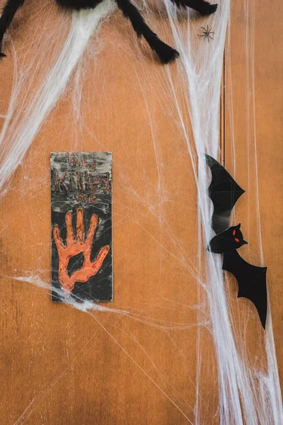 Door decorated with spider net, toy spiders, paper cut bat and sign plate with they killed me lettering — Stock Photo