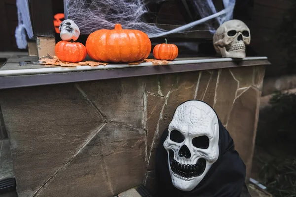 Citrouilles orange et crânes effrayants sur le porche décoré pour Halloween — Photo de stock