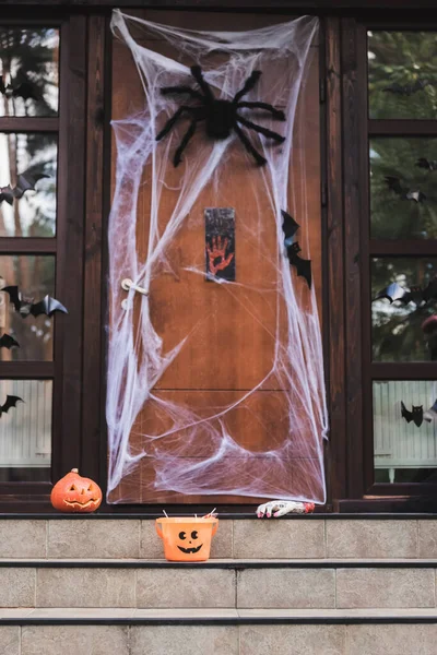 Cottage entrance decorated with spider net, paper cut bats, carved pumpkin and halloween bucket — Stock Photo