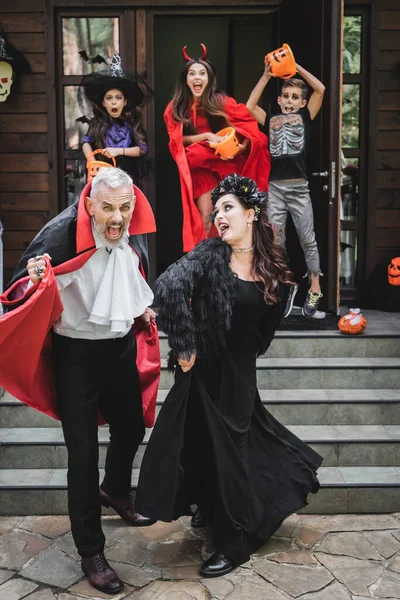 Налякана пара в костюмах Хеллоуїна кричить, коли закінчується будинок від жахливих дітей — стокове фото
