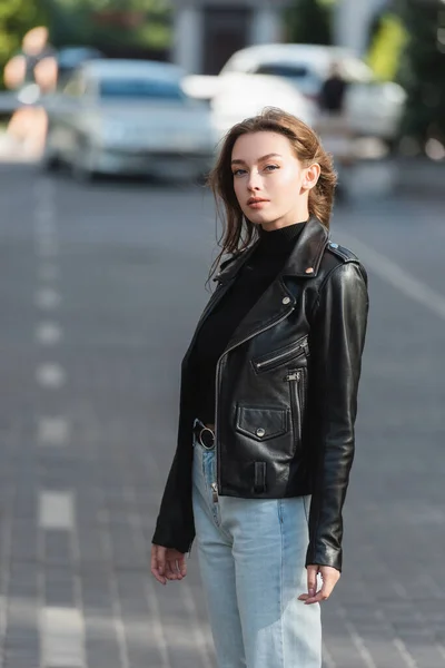 Hübsche junge Frau in schwarzer Lederjacke steht draußen — Stockfoto