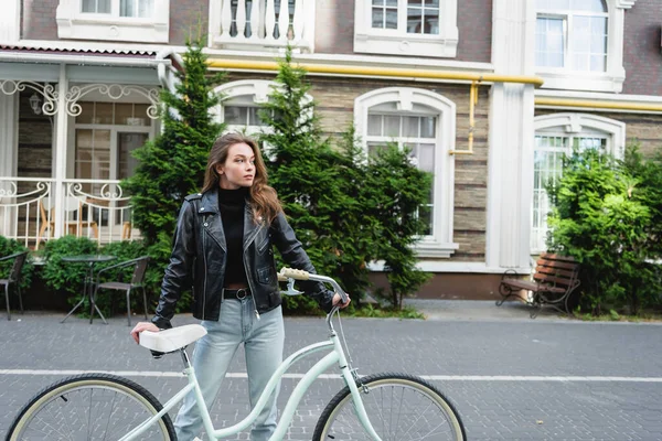 Jeune femme branchée debout près de vélo sur la rue urbaine de l'Europe — Photo de stock