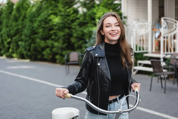 Весела молода жінка стоїть біля велосипеда на міській вулиці Європи — стокове фото