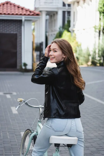 Pleased young woman riding bicycle on urban street of europe — Stock Photo