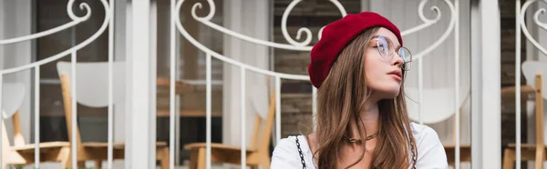 Pretty young woman in red beret and eyeglasses looking away outside, banner — Stock Photo