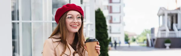 Felice giovane donna in berretto rosso e trench beige con coppa di carta, banner — Foto stock