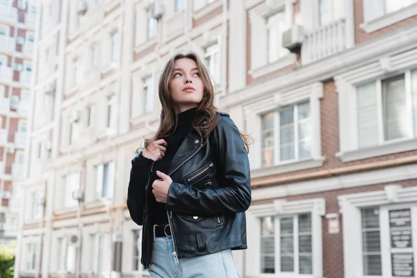 Jeune femme à col roulé noir et veste en cuir sur la rue urbaine d'Europe — Photo de stock