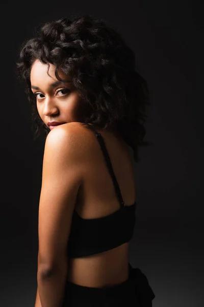 Young african american woman looking at camera and posing on black — Stock Photo