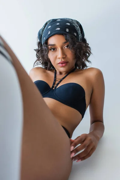 Moda joven afroamericana mujer en traje de baño y bandana posando en gris - foto de stock