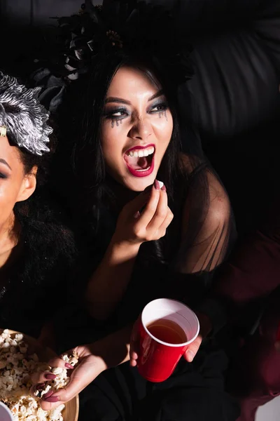 Asiatico donna con spaventoso smorfia mangiare popcorn durante halloween festa — Foto stock