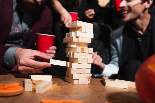 Частичный вид размытых друзей, играющих в деревянные блоки во время вечеринки на Хэллоуин — стоковое фото