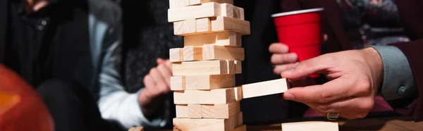 Cropped view of blurred friends playing wood blocks game during party, banner — Stock Photo