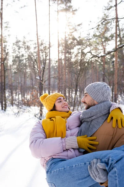 Sorrindo homem levantando namorada no parque de inverno — Fotografia de Stock