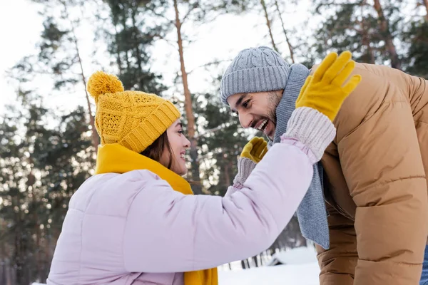 Vista laterale di coppia eccitata in sciarpe e cappelli nel parco invernale — Foto stock