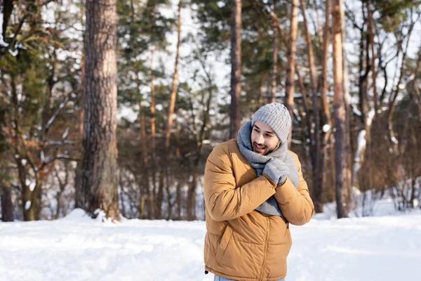 Homme souriant en vêtements chauds debout dans le parc d'hiver — Photo de stock